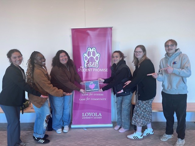 The photo displays the student Promise step and repeat in the enter of six student leaders three on each side. The students are holding a student leader appreciation sign in the middle of the picture. 